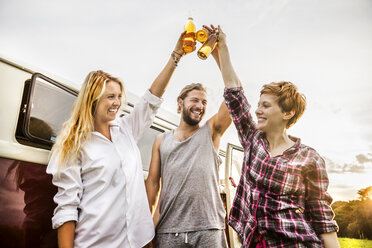 Glückliche Freunde stoßen mit Bierflaschen an einem Lieferwagen in ländlicher Landschaft an - FMKF04602