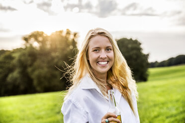 Porträt einer glücklichen Frau beim Biertrinken in einer ländlichen Landschaft - FMKF04605