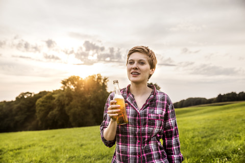 Smiling woman drinking beer in rural landscape stock photo