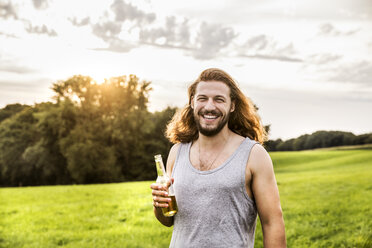Porträt eines glücklichen Mannes beim Biertrinken in einer ländlichen Landschaft - FMKF04607