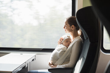 Mother with baby girl traveling by train looking out of window - DIGF02869