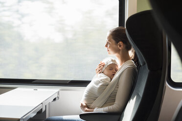 Mutter mit kleinem Mädchen reist mit dem Zug und schaut aus dem Fenster - DIGF02869