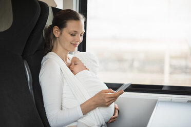 Mutter mit kleinem Mädchen reist mit dem Zug und schaut auf ihr Handy - DIGF02870