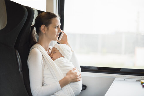 Mutter mit kleinem Mädchen reist mit dem Zug und spricht mit dem Handy - DIGF02871