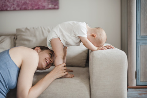 Happy mother with baby girl on couch at home stock photo