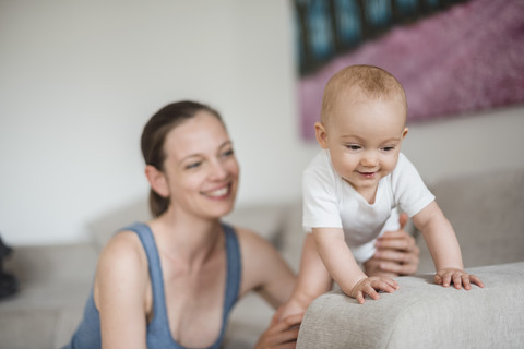 Happy baby girl with mother on couch stock photo