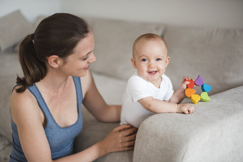 Happy baby girl with mother playing on couch - DIGF02886