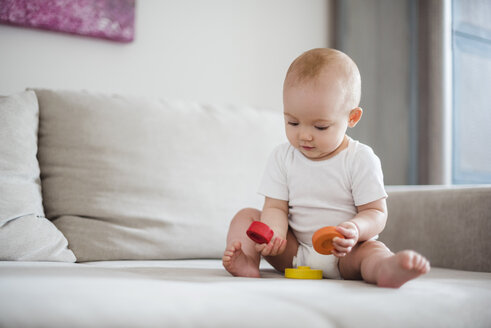 Baby girl playing on couch at home - DIGF02896