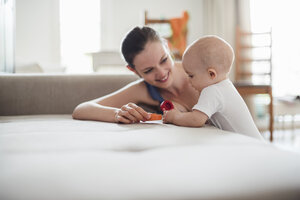 Baby-Mädchen mit Mutter spielen auf der Couch zu Hause - DIGF02898