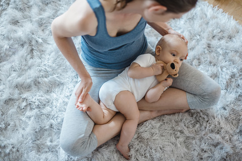 Baby girl lying in mother's lap on carpet stock photo