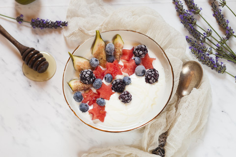 Schale mit griechischem Joghurt mit Feige, Wassermelone, gefrorenen Beeren und Lavendelhonig, lizenzfreies Stockfoto