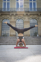 Young woman doing a headstand during a yoga exercise in the city - JUNF00933