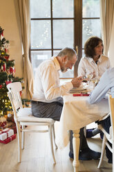 Älterer Mann mit Familie beim Weihnachtsessen am Tisch - HAPF02195