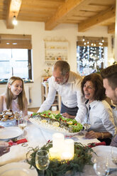 Älterer Mann serviert Fisch für die Familie beim Weihnachtsessen - HAPF02204