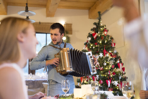 Junger Mann spielt Akkordeon am Weihnachtstisch - HAPF02205