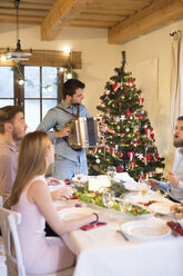 Junger Mann spielt Akkordeon am Weihnachtstisch - HAPF02207