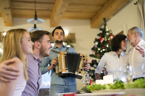 Junger Mann spielt Akkordeon für seine Familie zu Weihnachten, lizenzfreies Stockfoto