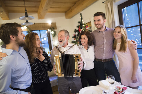 Älterer Mann spielt Akkordeon für eine glückliche Familie zu Weihnachten - HAPF02213