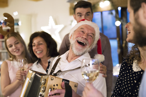 Älterer Mann spielt Akkordeon für eine glückliche Familie zu Weihnachten, lizenzfreies Stockfoto