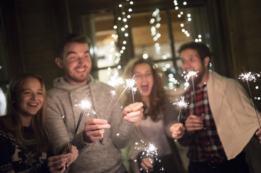 Happy friends holding sparklers outdoors at night - HAPF02222