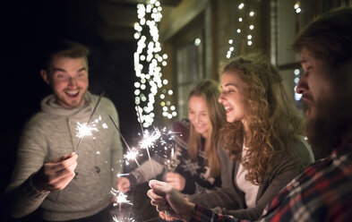 Happy friends holding sparklers outdoors at night - HAPF02224