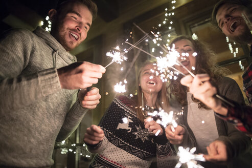 Happy friends holding sparklers outdoors at night - HAPF02225