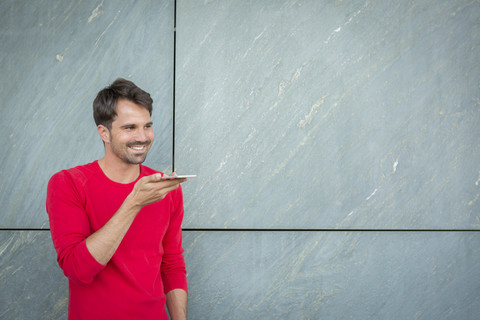 Mann hinterlässt eine Sprachnachricht mit seinem Smartphone, lizenzfreies Stockfoto