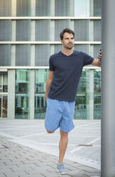 Jogger training in the city, stretching to warm up - JUNF00974