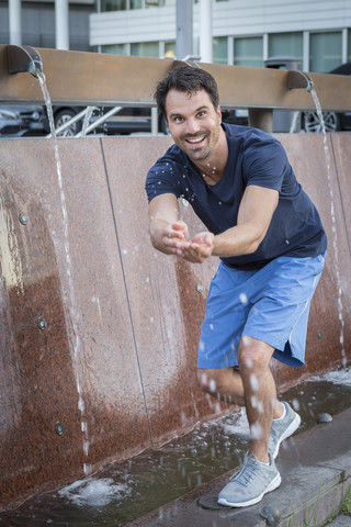 Joggerin trainiert in der Stadt, spritzt Wasser in einem Brunnen, lizenzfreies Stockfoto