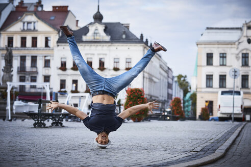 Man having fun doing headstand on square in the city - BSZF00078