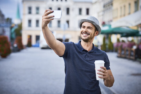 Mann macht Selfie in der Stadt mit Kaffee und Filzhut - BSZF00080