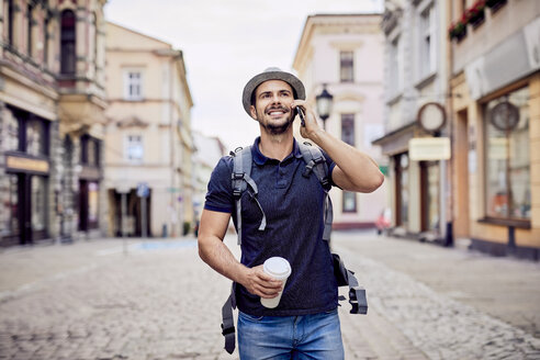 Traveler talking on the phone while walking down city street - BSZF00085