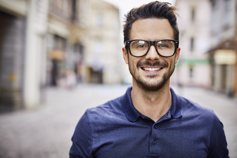 Porträt eines lächelnden Mannes mit Brille in der Stadt, lizenzfreies Stockfoto