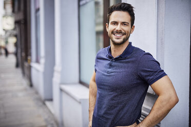 Smiling man standing on city street - BSZF00089