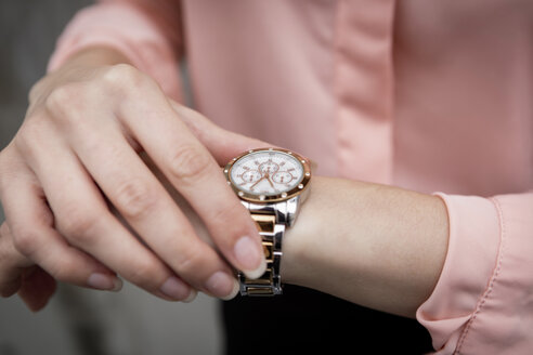 Portrait of a young businesswoman looking on her wristwatch - JUNF00983