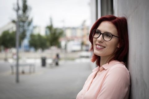 Lächelnde Geschäftsfrau lehnt an der Wand, lizenzfreies Stockfoto