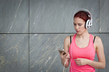 Frau in Sportkleidung trägt Kopfhörer und hört Musik - JUNF01000
