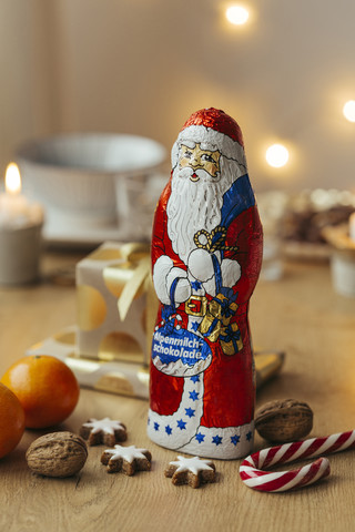 Schokoladenweihnachtsmann mit Geschenken, Früchten und Zimtsternen, lizenzfreies Stockfoto