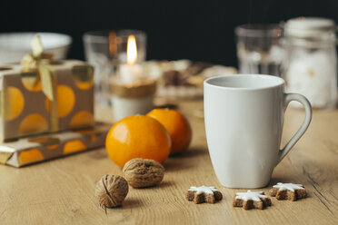 Tasse Tee, Mandarinen, Walnüsse, Zimtsterne und Weihnachtsgeschenke im Hintergrund - JHAF00005