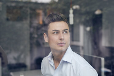 Young businessman behind glass pane in office - PNEF00171