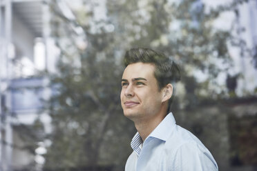 Portrait of smiling young businessman looking out of window - PNEF00173