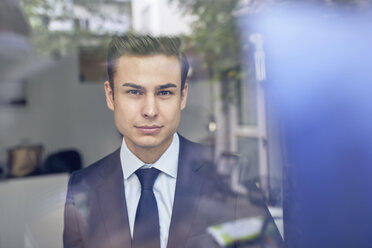 Junger Geschäftsmann hinter Glasscheibe im Büro - PNEF00180