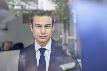 Young businessman behind glass pane in office - PNEF00180