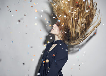 Young woman tossing hair under shower of confetti - PNEF00185
