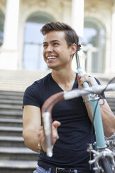 Portrait of happy young man with racing cycle on his shoulder - PNEF00198