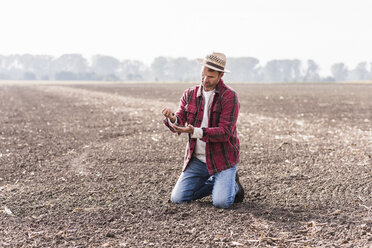 Landwirt kniet auf gepflügtem Feld und untersucht den Boden - UUF11915