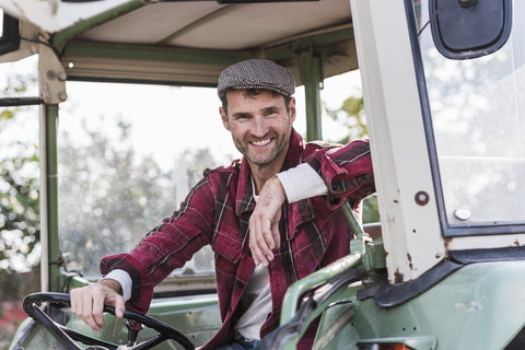 Porträt eines selbstbewussten Landwirts auf einem Traktor, lizenzfreies Stockfoto
