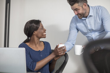 Lächelnde Kollegen mit Kaffeetassen, die sich im Büro unterhalten - ZEF14658