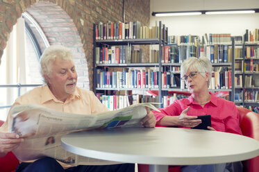 Älteres Paar mit Zeitung und E-Book in einer Stadtbibliothek - FRF00578