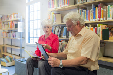 Älteres Paar mit Laptop und Buch in einer Stadtbibliothek - FRF00581
